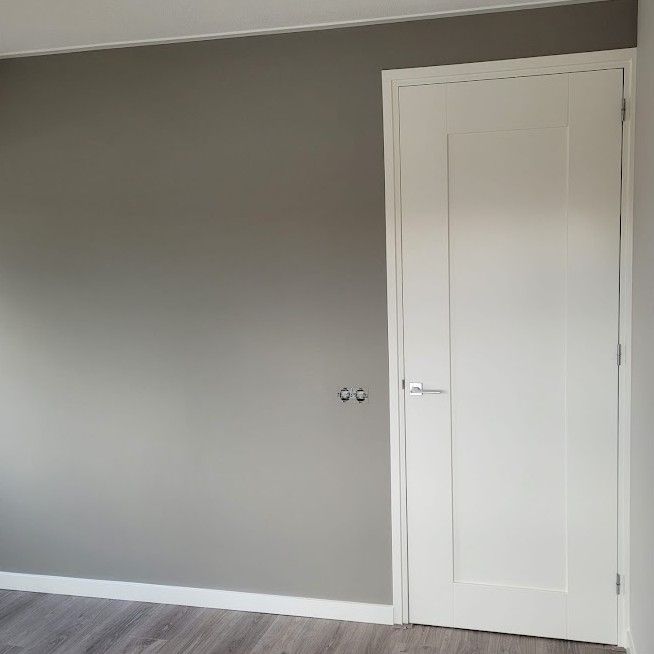 Grijze wand naast een witte paneeldeur
