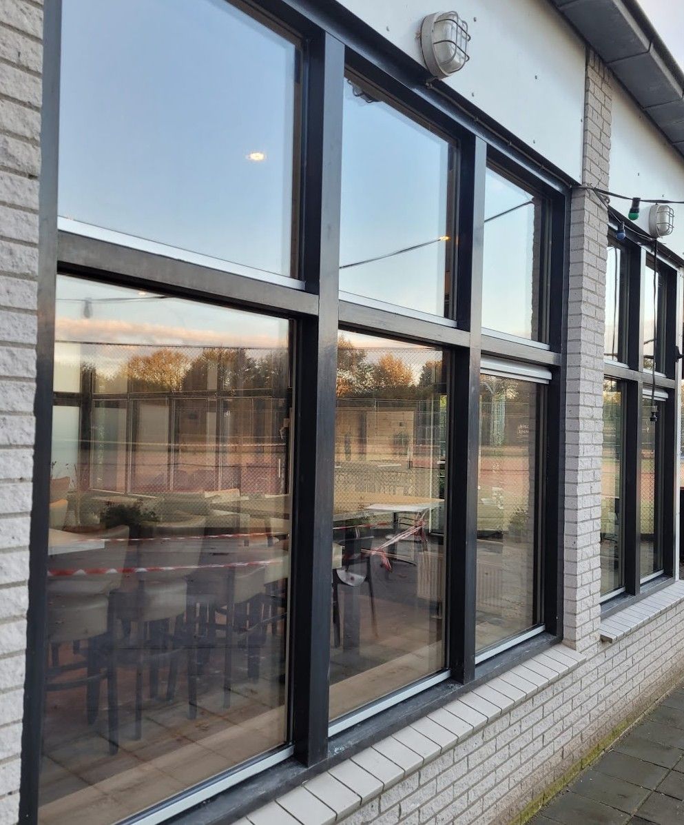 Zwarte kozijnen met nieuw glas aan de buitenkant van het clubhuis