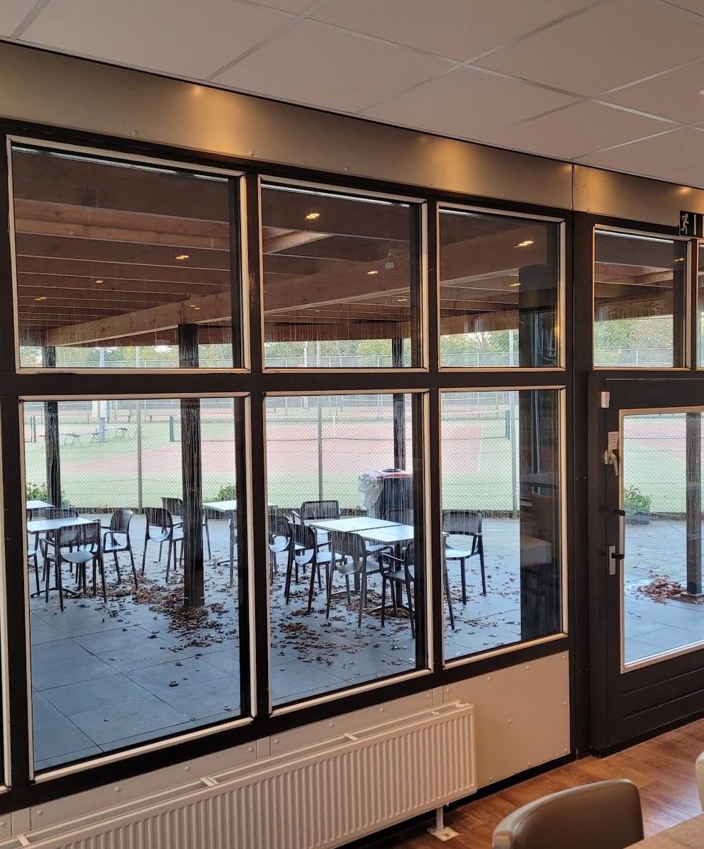 De nieuwe glazen pui van binnenuit, met zicht op de tennisbanen