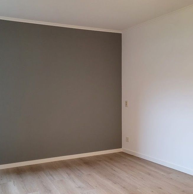 Donkergrijze accentwand in een lichte kamer